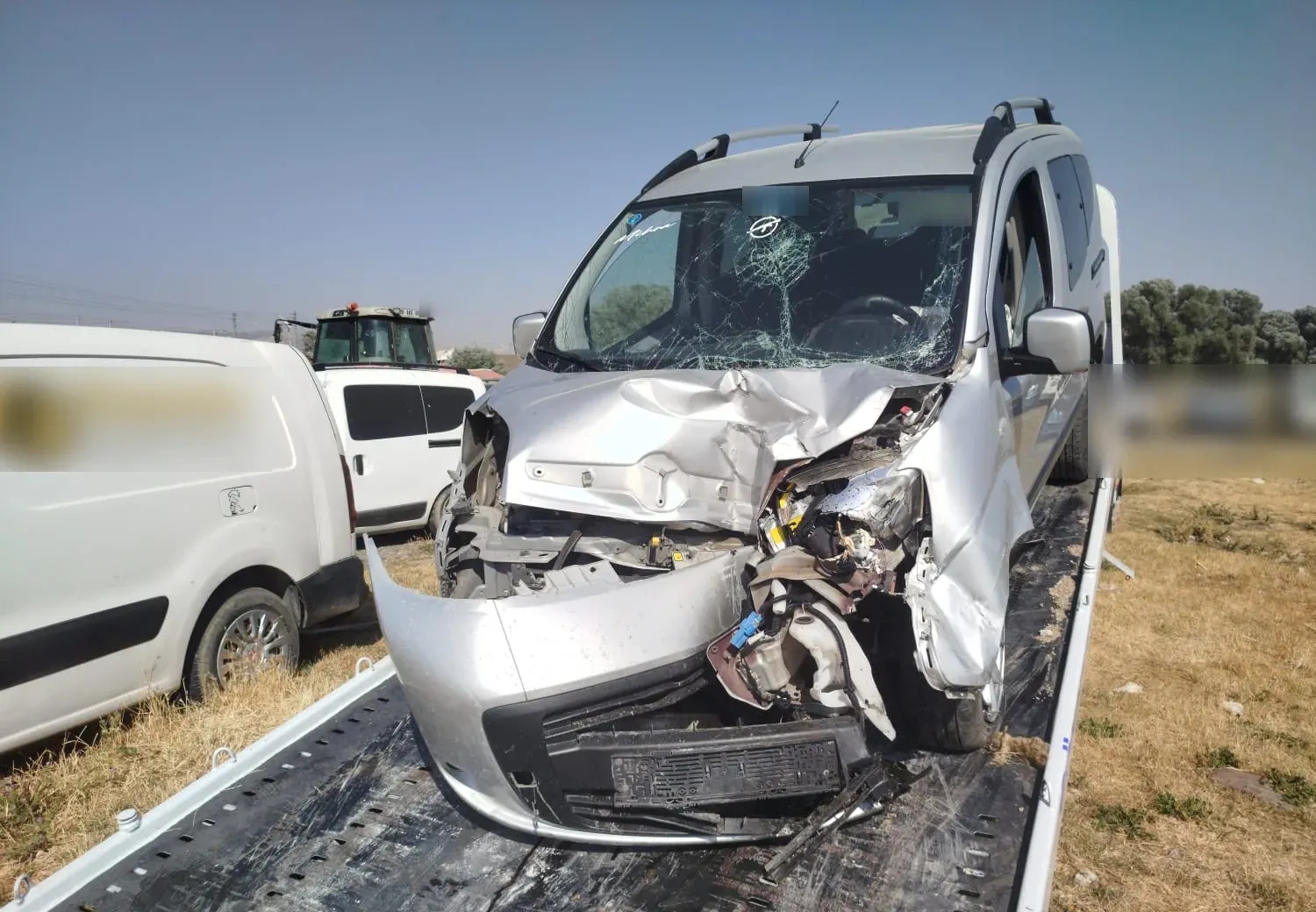 Ön kısmı ağır hasarlı gümüş Fiat Fiorino, çekici platformuna yüklenmiş halde.
