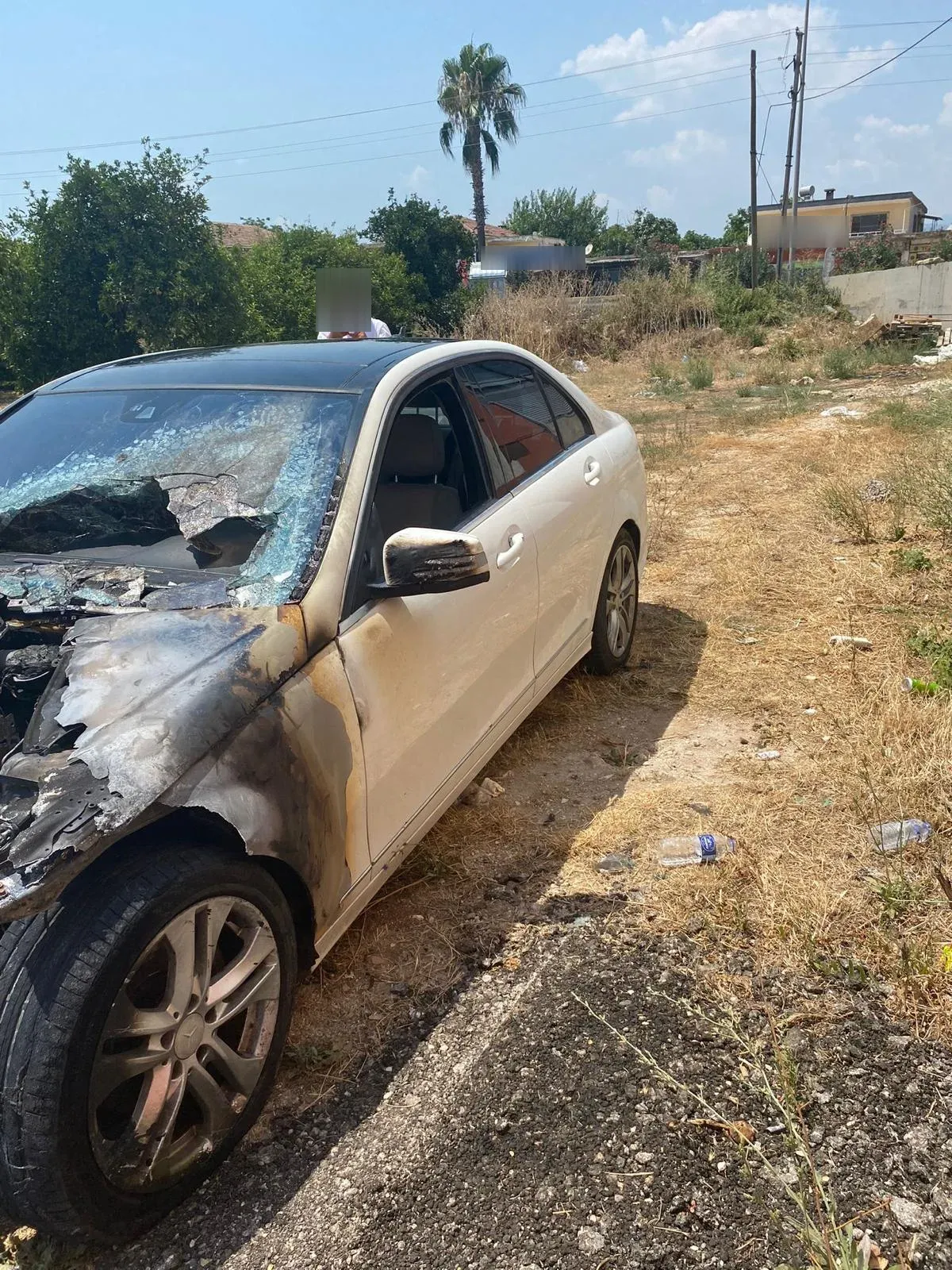 Ön bölümü yanarak kömürleşmiş, ön camı ve kaputu tahrip olmuş beyaz Mercedes-Benz C serisi.