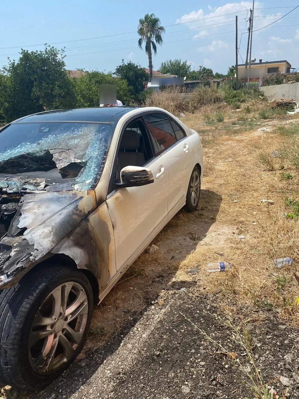 Ön bölümü yanarak kömürleşmiş, ön camı ve kaputu tahrip olmuş beyaz Mercedes-Benz C serisi.